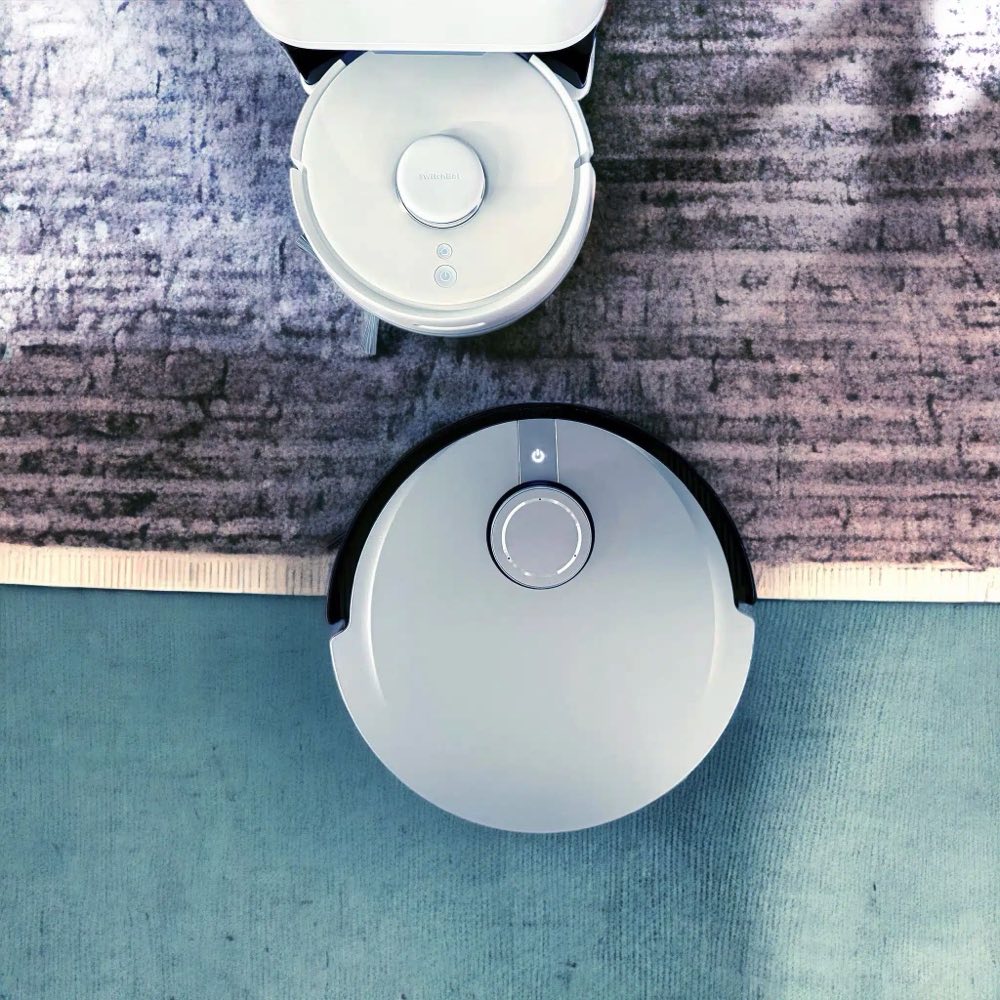 Two robot vacuums on a rug seen from above